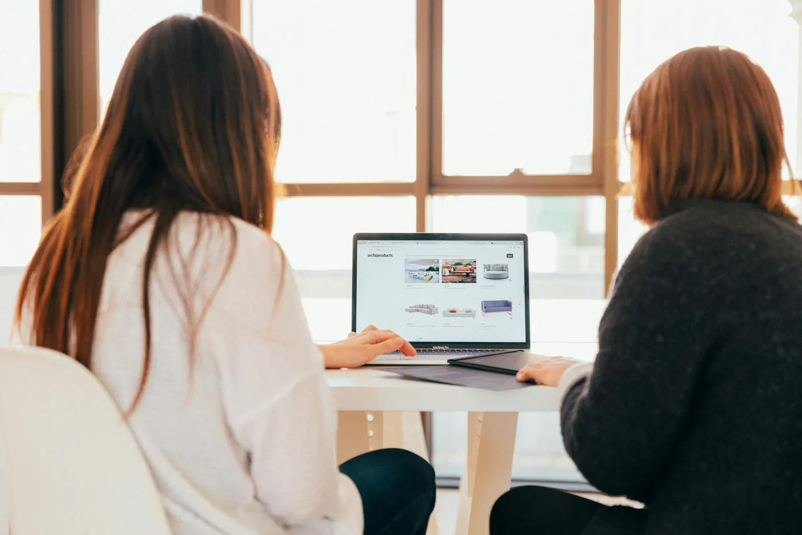 Duas pessoas analisando um site em um notebook